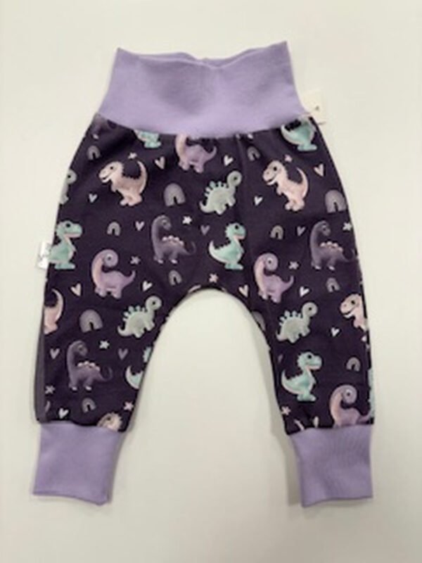 Dětské kalhoty s dinosaury na fialovém pozadí.