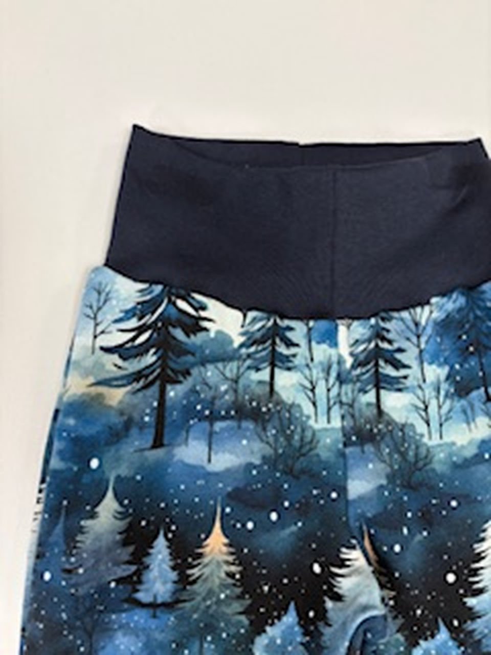 Zimní lesní vzor na kalhotách s tmavým pasem.