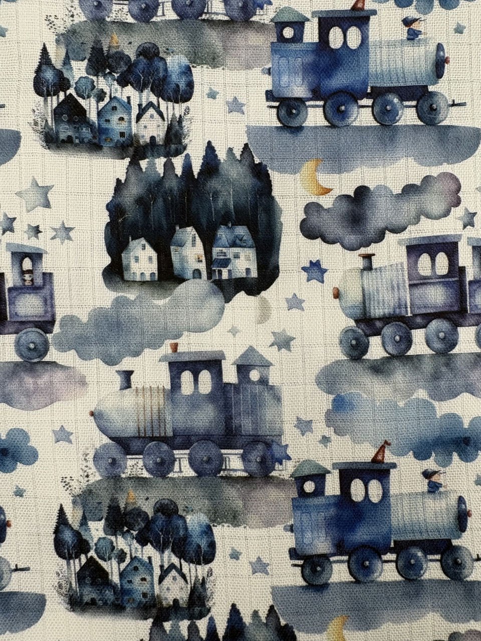 Barevné ilustrace vlaků a stromů na látce.