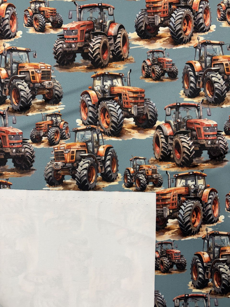 Vzor s červenými traktory na modrém pozadí.
