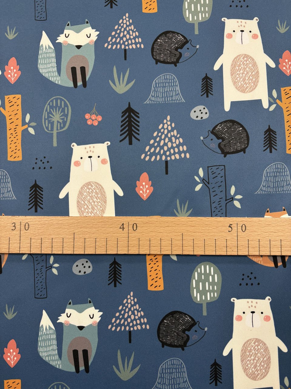 Barevná látka s lesními zvířaty a stromy.