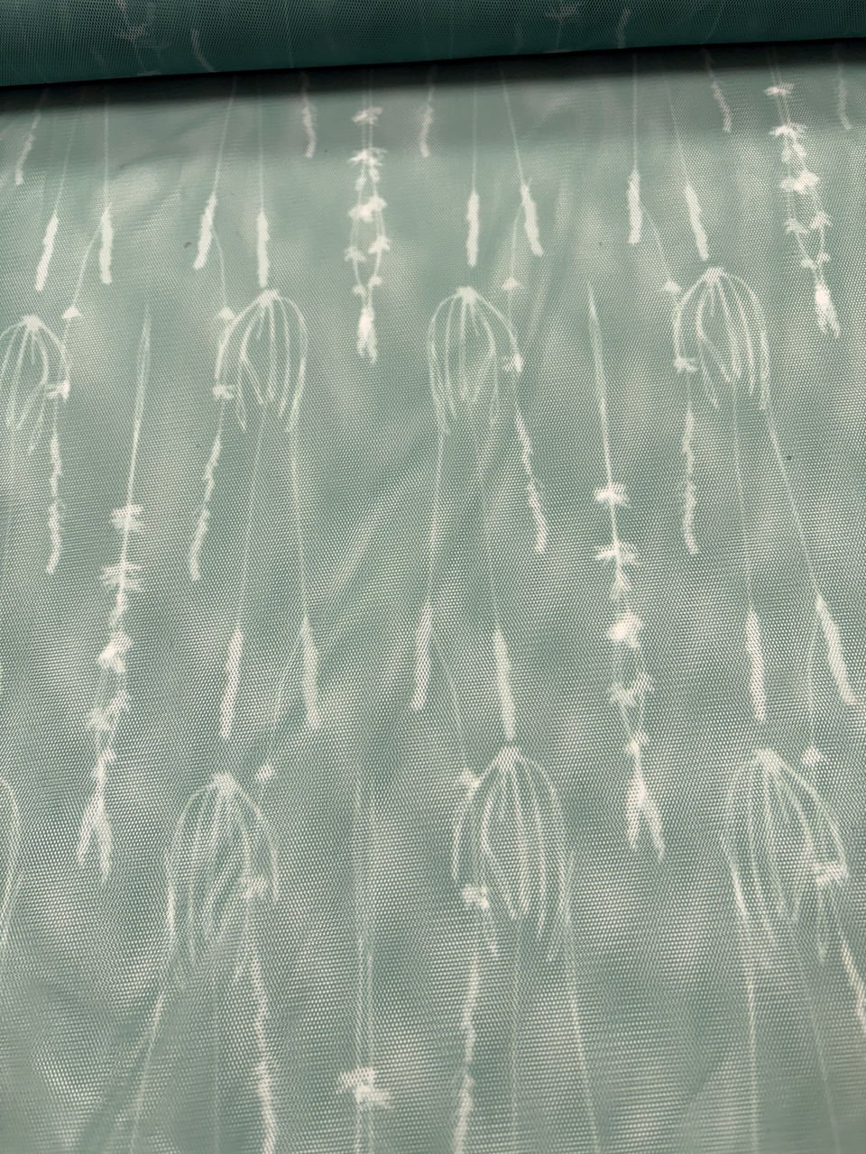 Zelená látka s bílým vzorem květin.