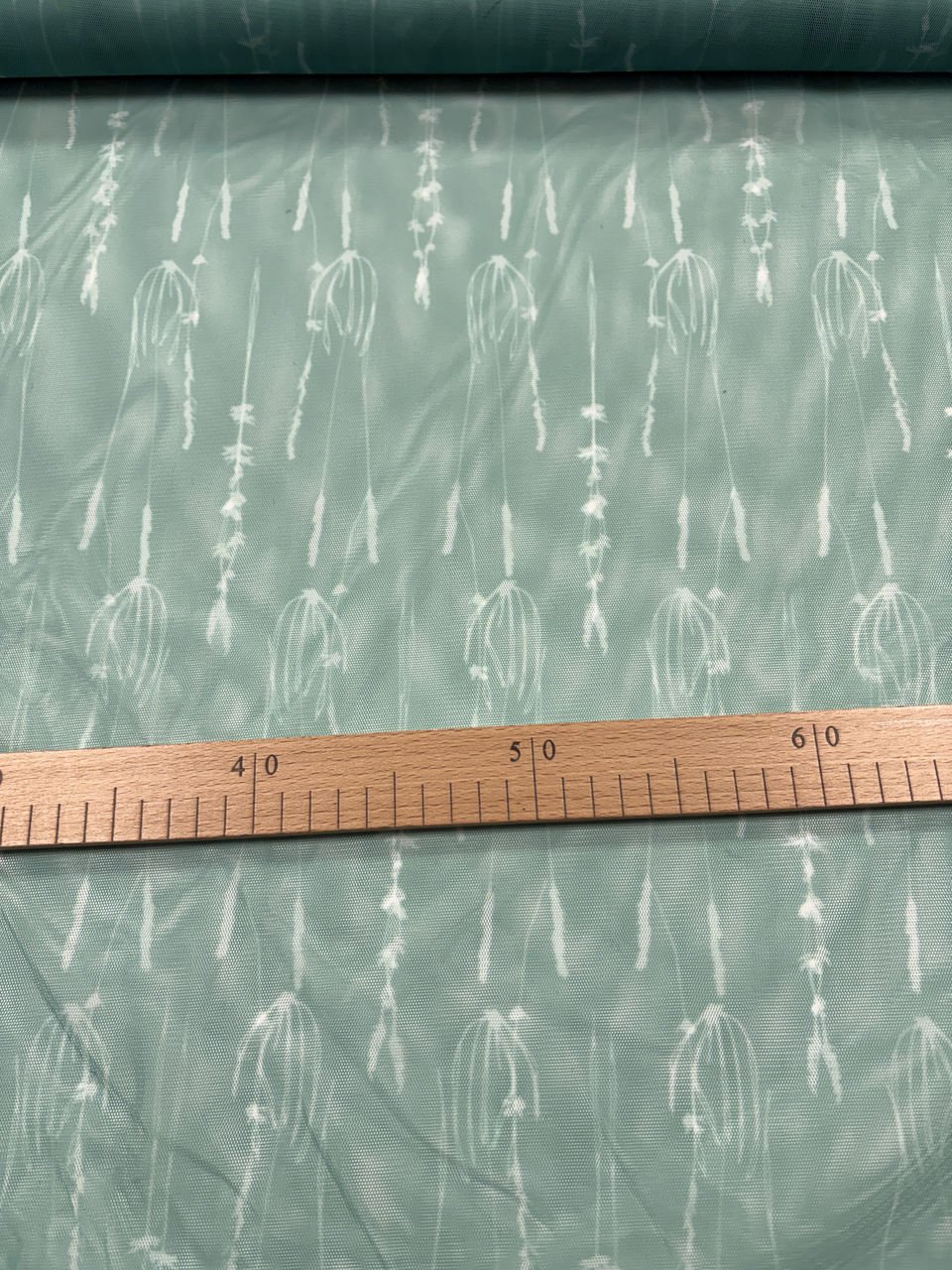 Zelená látka s jemným bílým vzorem, měřítko ukazuje.