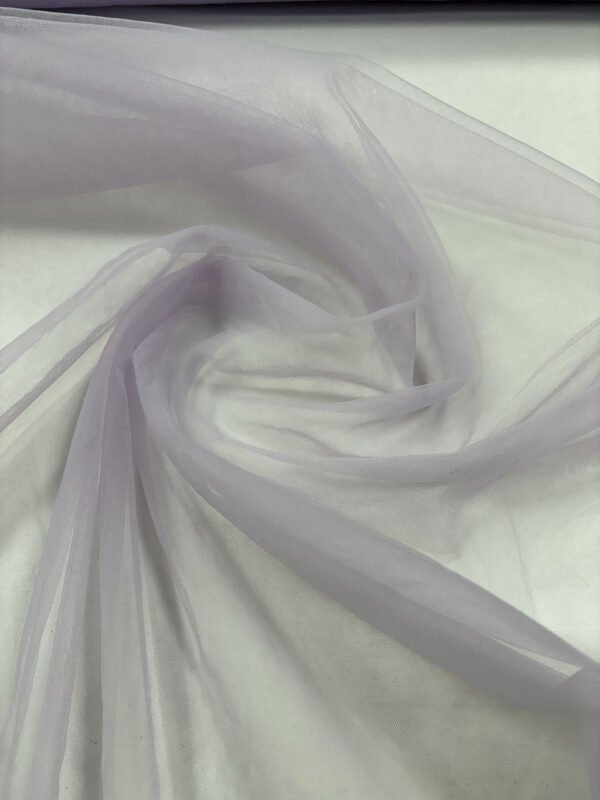 Světlá lila průhledná textilie rozložená na stole.
