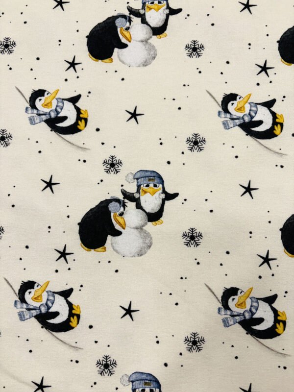 Tučňáci se šálami a čepicemi na sněhu.