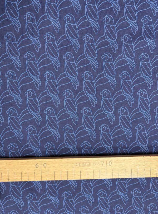 Modrá látka s motivem papoušků a pravítkem.