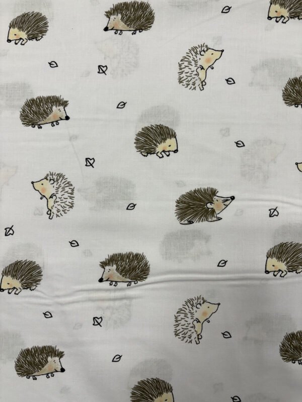 Textilní vzor s kreslenými ježky a listy.